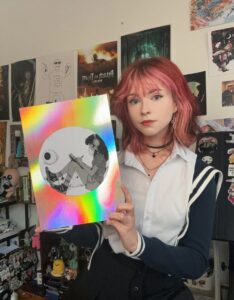 Comic artist Zoe holding her holographic print